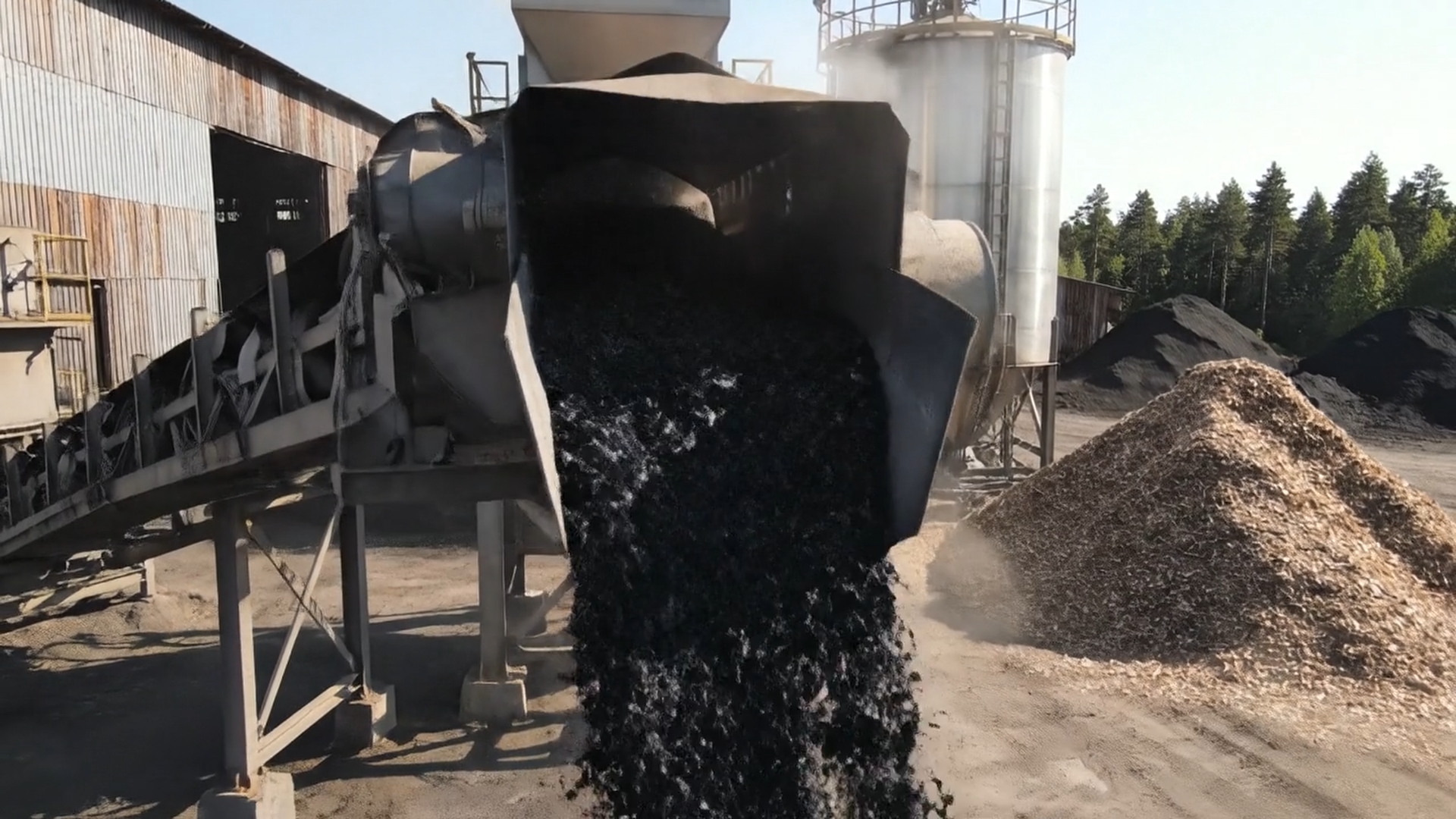 Biochar qui sort du four de pyrolyse : charbon noir en flux continu